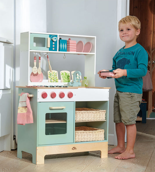 Child playing with a toy kitchen set in a room.