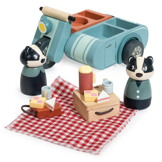 Wooden toy car with two badger figures and picnic items on a red checkered cloth