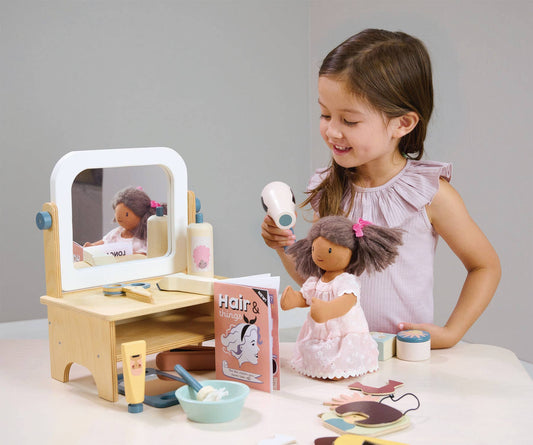 Young girl playing with a doll and toy vanity set
