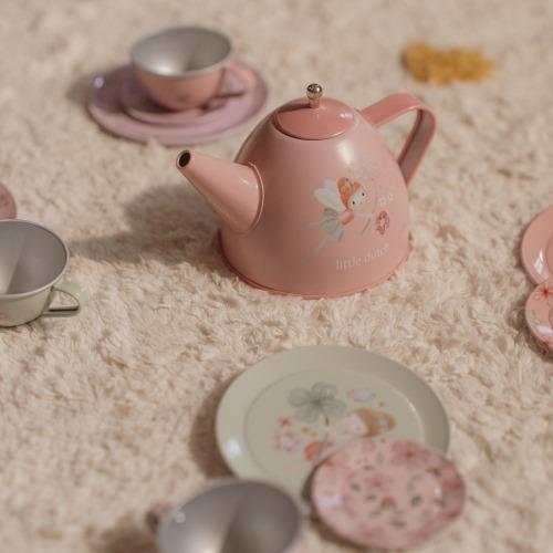 Children's toy tea set with a pink teapot, four cups, four saucers, and four cake pieces, all laid out on a white surface.
