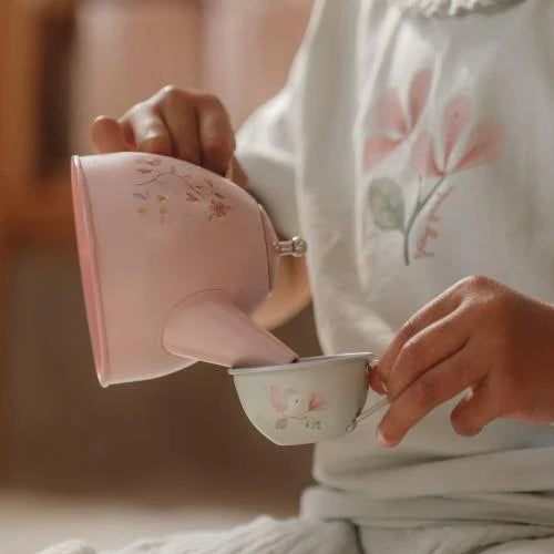 Child holding a pink teapot and cup with floral designs, wearing a floral shirt. Little Dutch Fairy Garden Tea Set