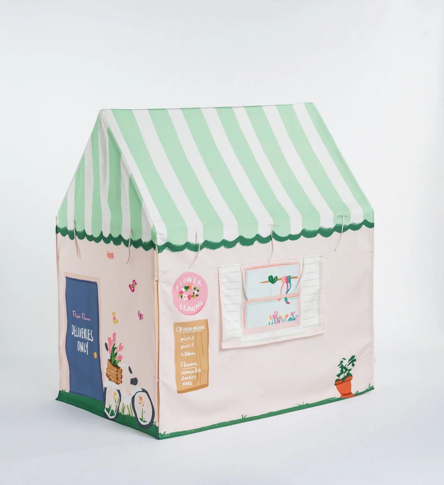 A children's fabric playhouse shaped like a small house with a mint green and white striped awning, a pale pink body, and decorative printed details including a blue door, window, bicycle, and potted plant on a white background.