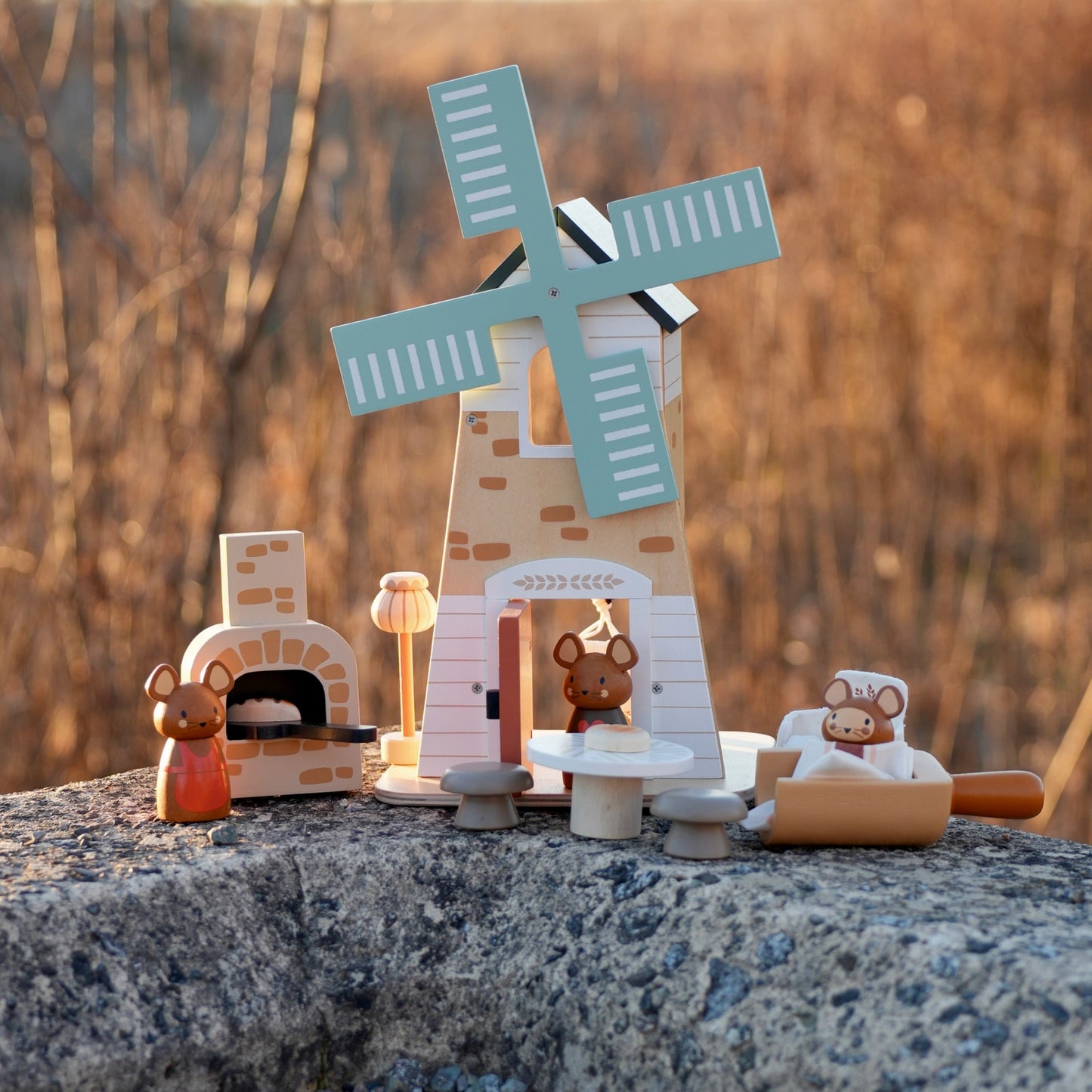 Wooden nativity scene with a windmill and animals on a stone surface. Tender Leaf Toys Penny Windmill