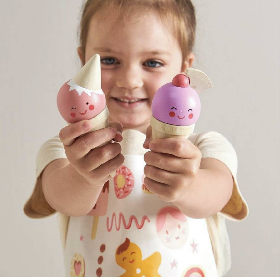 Child holding two toy ice cream cones with a plain background. Scoops and Smiles ice cream wooden toy stand. Perfect for toddlers. 