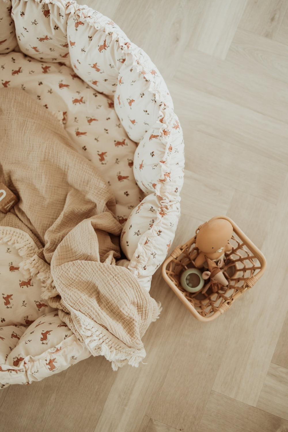 Baby crib with white mattress and brown blanket on a wooden floor
