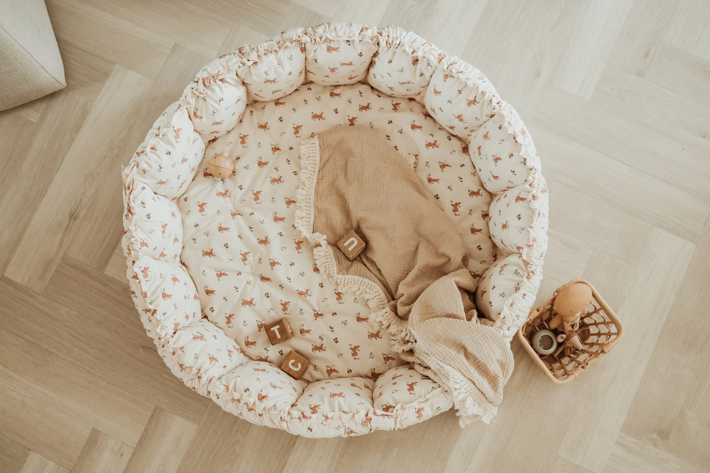 Round baby crib with floral pattern on a wooden floor
