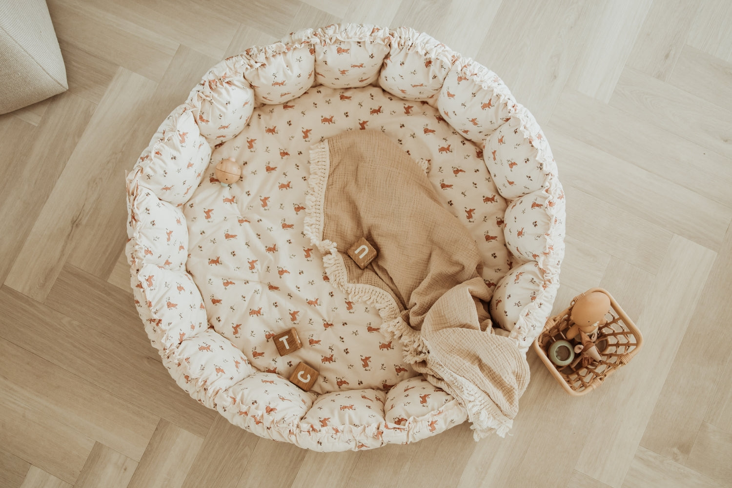 Round baby crib with floral pattern on a wooden floor