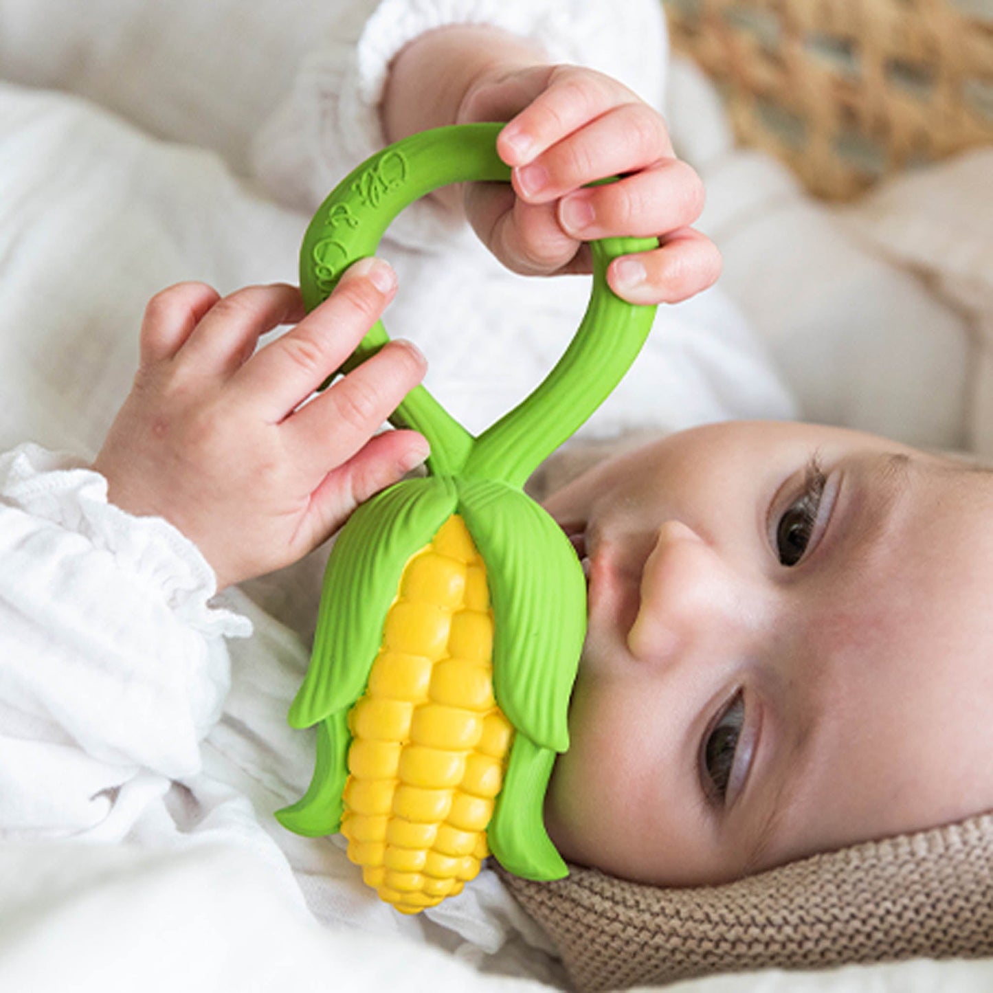 Baby holding a corn-shaped teething toy