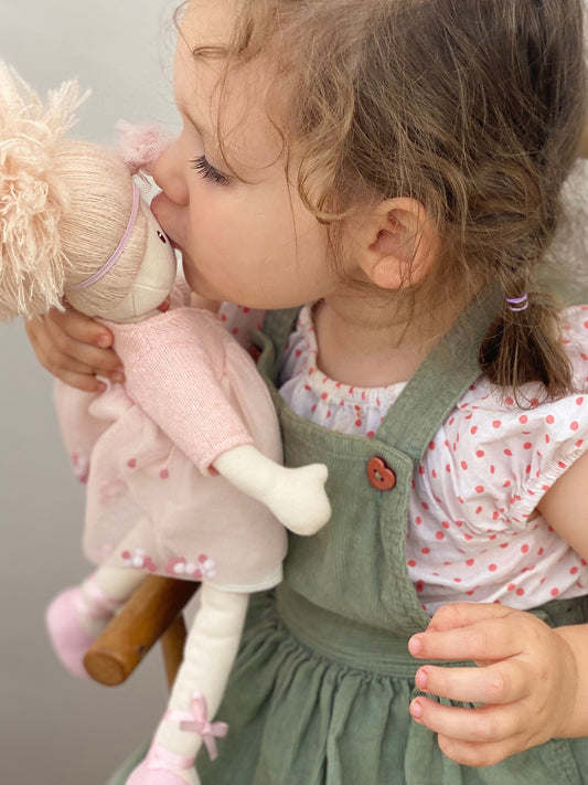 Child kissing a plush toy with a neutral background