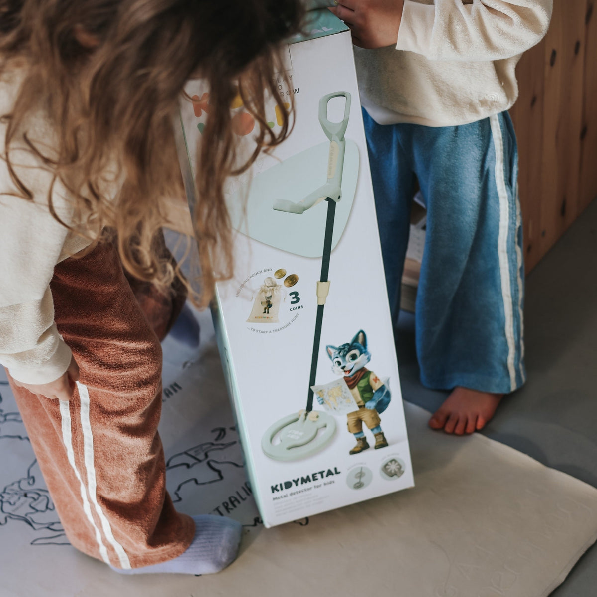 Two children looking at a KibyMetal product box on the floor.