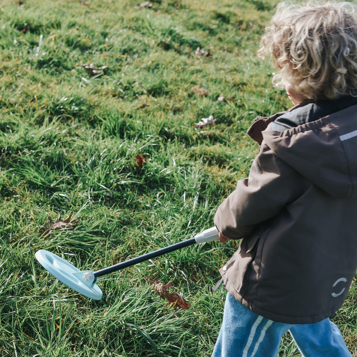 Child playing with a toy in a grassy field