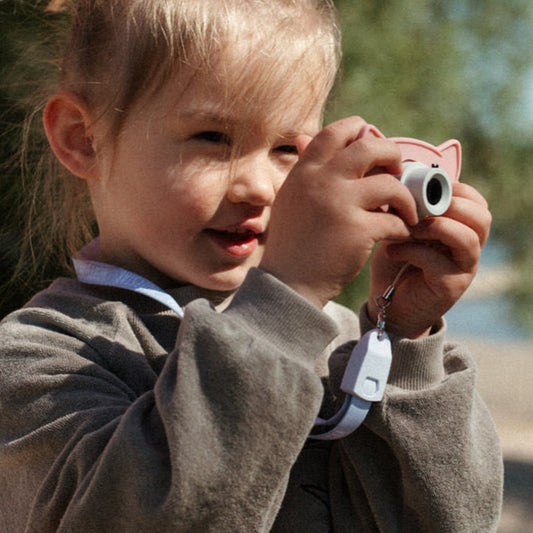 Little girl holding pink camera 