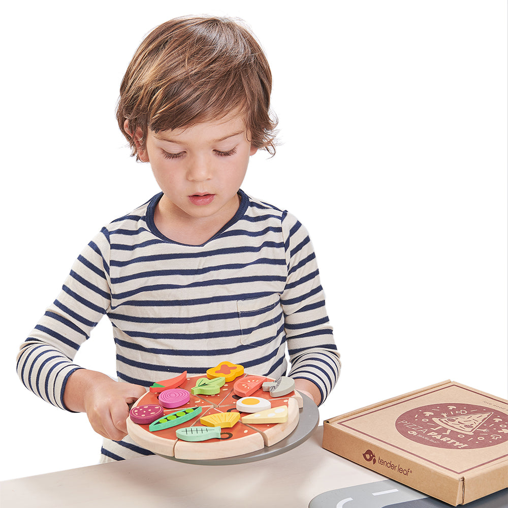 Child playing with a toy pizza set on a white background