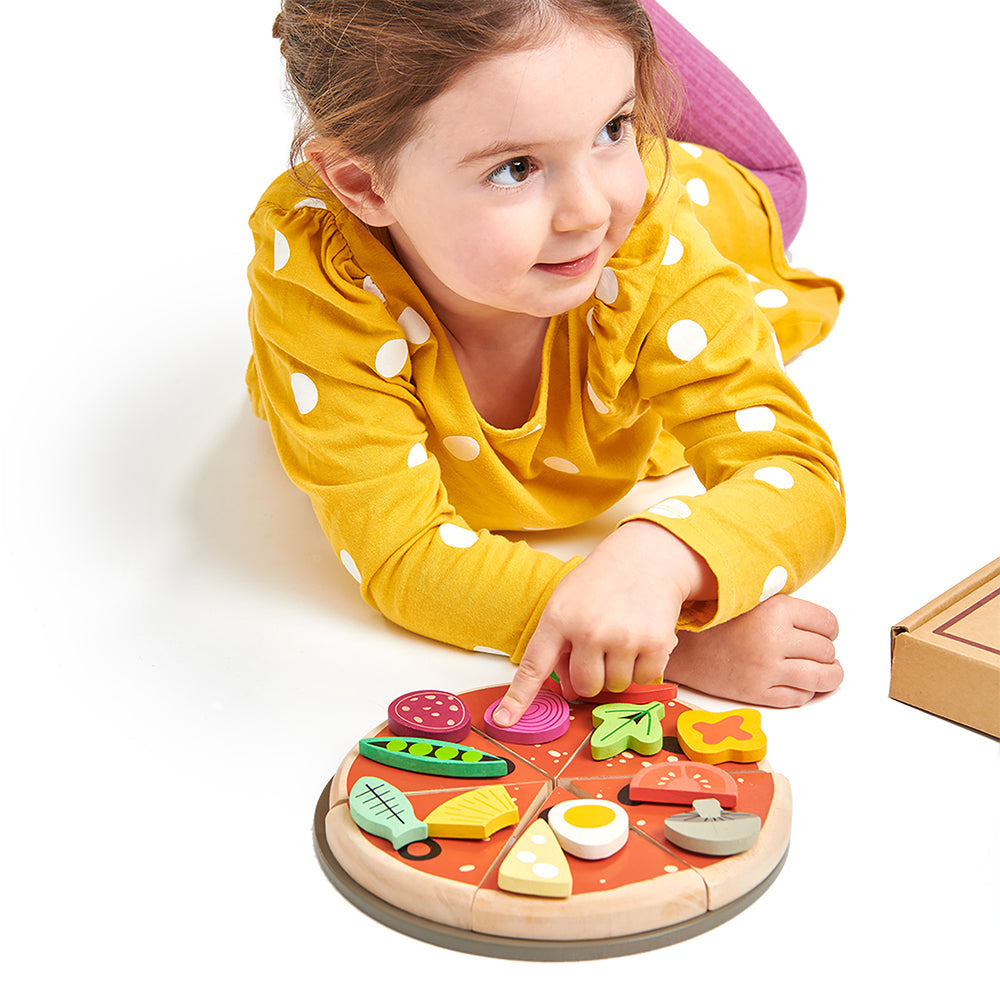 Child playing with a toy pizza set on a white background