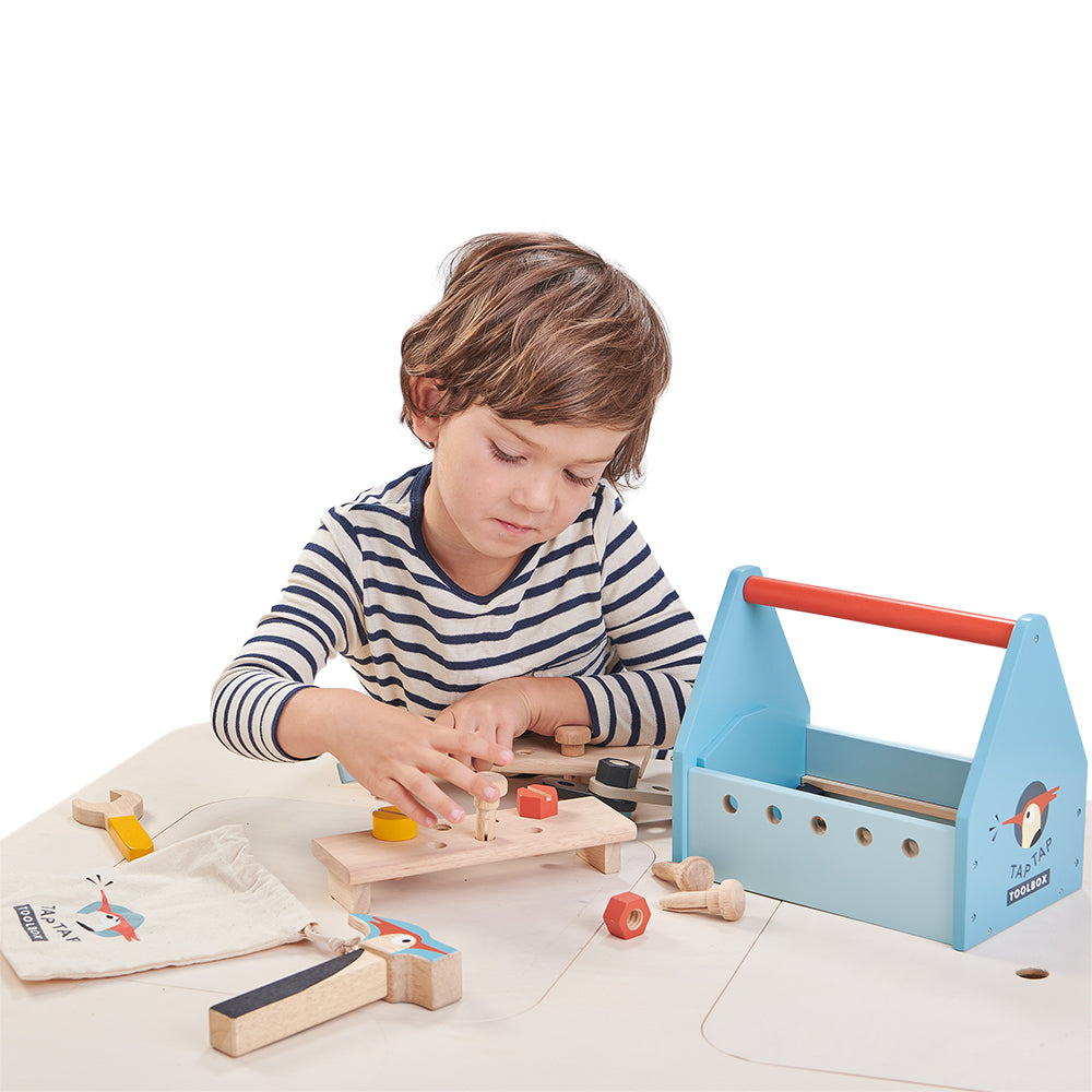 Child playing with a wooden tool set on a white background