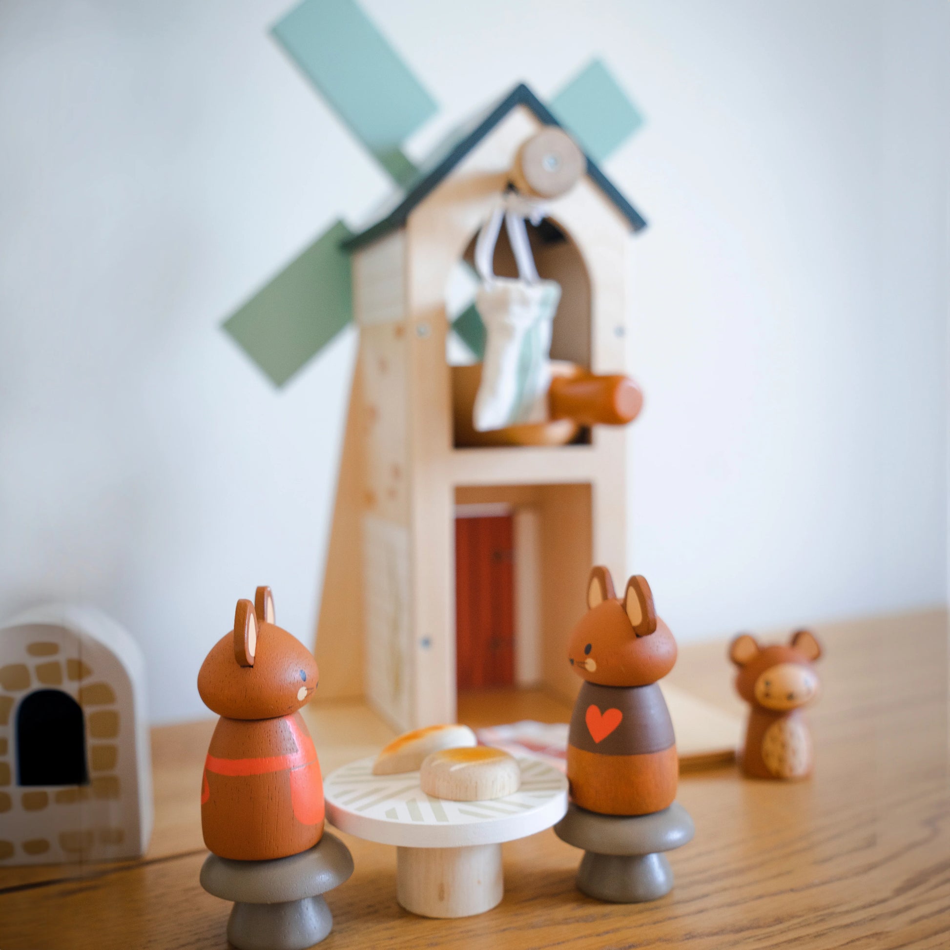 Wooden toy squirrels on a wooden surface with a windmill in the background Tender Leaf Toys Penny Windmill