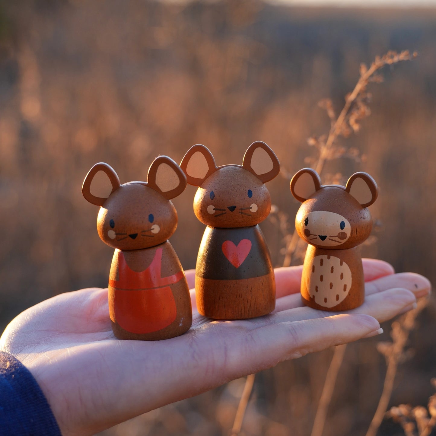Three small wooden mouse figurines held in a hand with a blurred natural background Tender Leaf Toys Penny Windmill