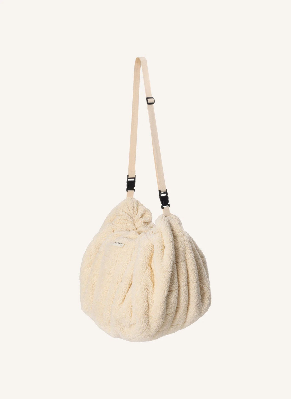 A cream-colored, textured faux fur shoulder bag with a matching adjustable shoulder strap, shown against a solid off-white background.