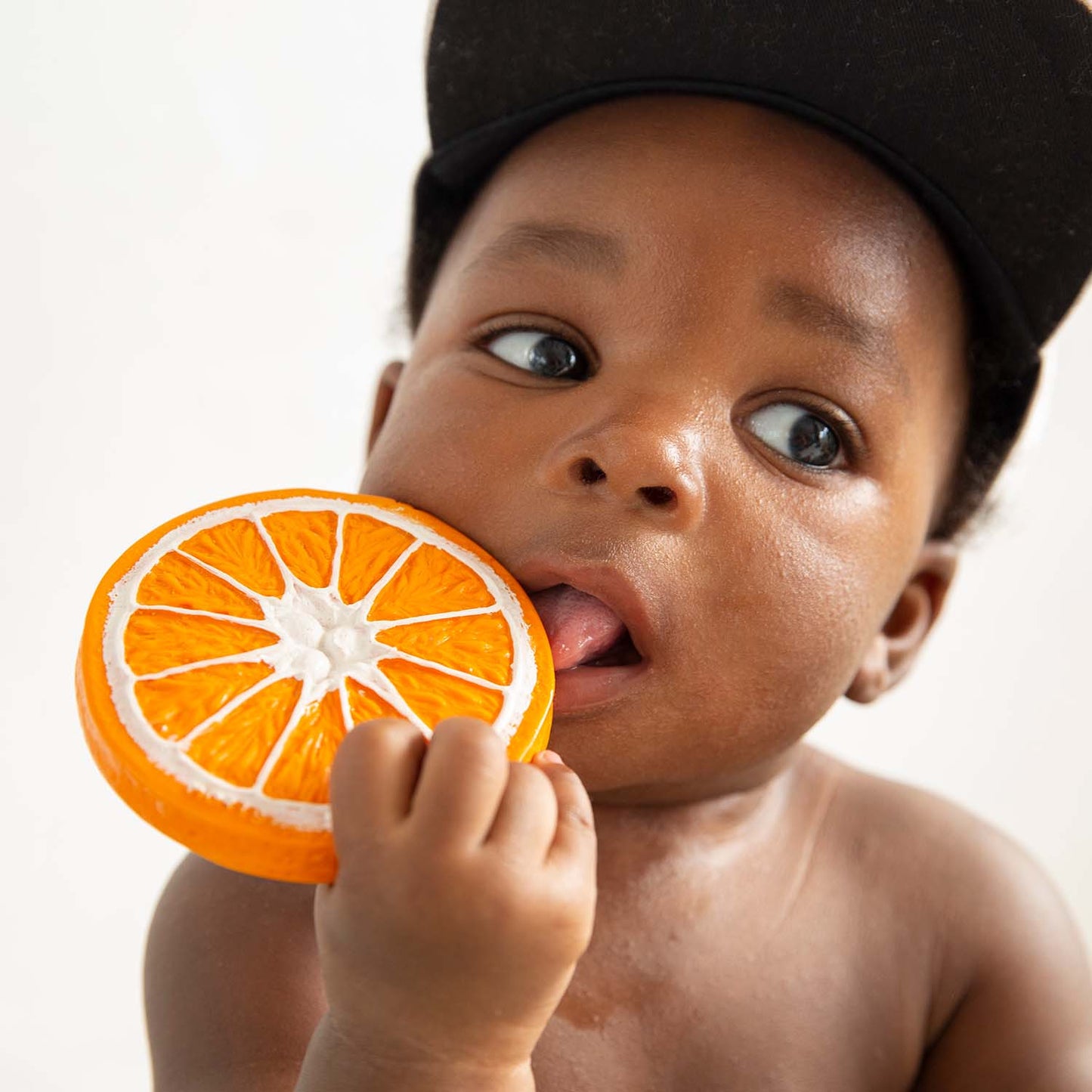 Baby holding an orange slice with a white background
